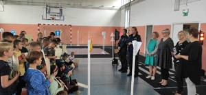 Policjantki na spotkaniu z dziećmi w sali gimnastycznej. Duża grupa dzieci stoi naprzeciwko policjantek.