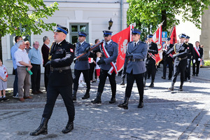 Poczet sztandarowy służb mundurowych. Na pierwszym planie poczet Komendy Powiatowej Policji w Olkuszu. Policjanci w galowym umundurowaniu niosą sztandar komendy id ac defiladowym krokiem .