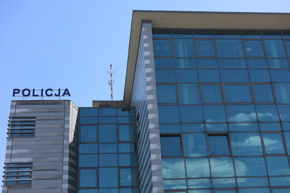 Budynek Komendy Powiatowej Policji w Olkuszu z napisem POLICJA. w tle błękitne bezchmurne niebo