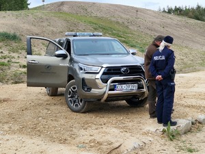 Policjantka i funkcjonariusz straży leśnej przy pojeździe straży. W tle pejzaż