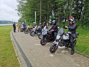 Motocykliści na motorach w równym rzędzie. w tle zalew wolbromski, las i chodnik