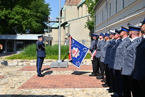 Komendant Wojewódzki Policji w Krakowie wita się ze sztandarem i oddaje honor. Przy nim stoi dowódca uroczystości. W tle Bazylika