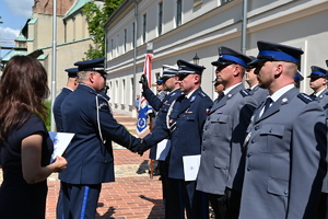 Komendant wojewódzki gratuluje awansowanemu policjantowi. Policjanci stoją w równym rzędzie.