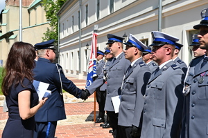 Komendant wojewódzki gratuluje awansowanemu policjantowi. Policjanci stoją w równym rzędzie (uścisk dłoni)