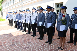 Policjantka i policjanci stoją w równym rzędzie w ręce trzymają akt mianowania.