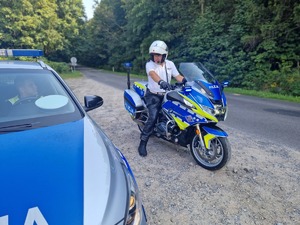 Policjant ruchu drogowego na motocyklu. w tle droga i las