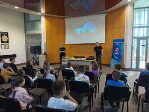 Technik kryminalistyki i dzielnicowy z dziećmi w auli komendy