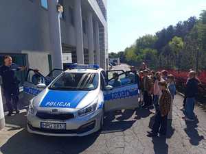Dzieci przy radiowozie przed budynkiem komendy