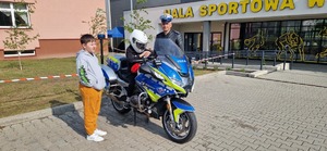 Dziecko na policyjnym motocyklu. Obok policjant ruchu drogowego