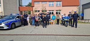 Dzieci wraz z policjantami na grupowym zdjęciu. Obok motocykle i radiowóz
