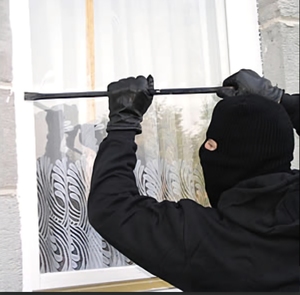 Zamaskowany mężczyzna próbujący wejść przez okno.