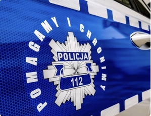odznaka policyjna umieszczona na radiowozie. Wokół niej napis &quot;pomagamy i chronimy&quot;.