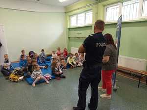 policjant i pracownica sanpeidu. Siedzący uczestnicy spotkania słuchają prelekcji