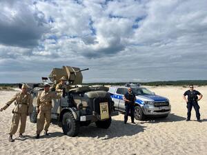 policjanci i aktorzy na tle radiowozu policyjnego.