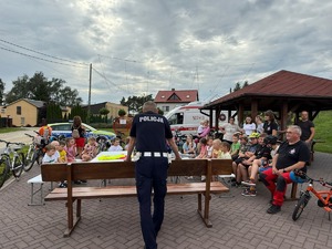 Policjant omawia zasady bezpieczeństwa ruchu drogowego dzieciom.