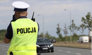 Policjant z Ruchu Drogowego mierzy prędkość samochodu.
