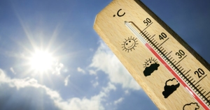 Termometr wskazujący wysoką temperaturę. w tle słońce na niebie.