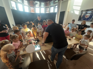 Technik kryminalistyki pokazujący dzieciom sprzęt na auli.