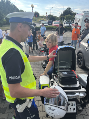 Policjant Ruchu Drogowego pokazujący sprzęt, na motocyklu siedzi dziecko.