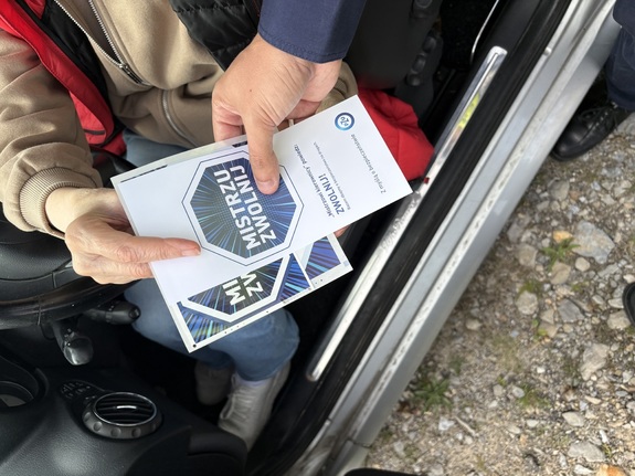 Policjant dający ulotkę kierowcy.
