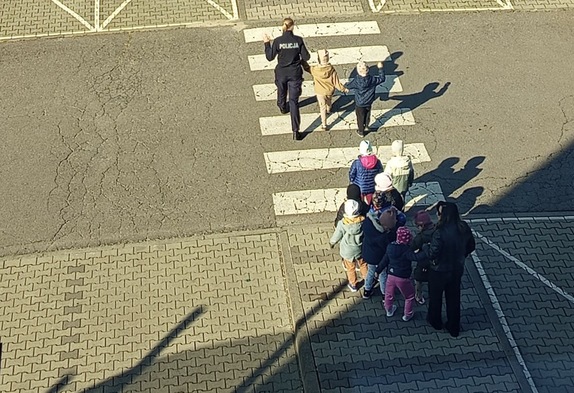 Dzieci przeprowadzane przez policjantkę przez pasy.