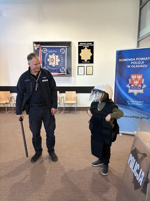 Dziecko w sprzęcie policyjnym z policjantem.