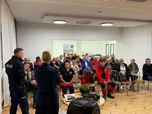 Seniorzy i strażacy podczas spotkania z funkcjonariuszami.