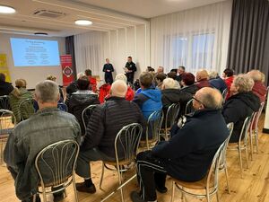 Seniorzy i strażacy podczas spotkania z funkcjonariuszami.