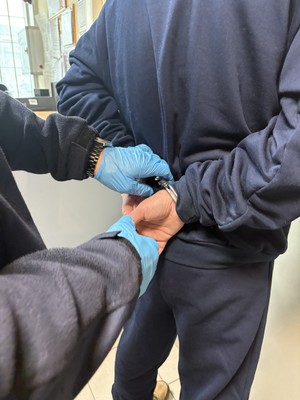 Policjant zakłada zatrzymanemu kajdanki.