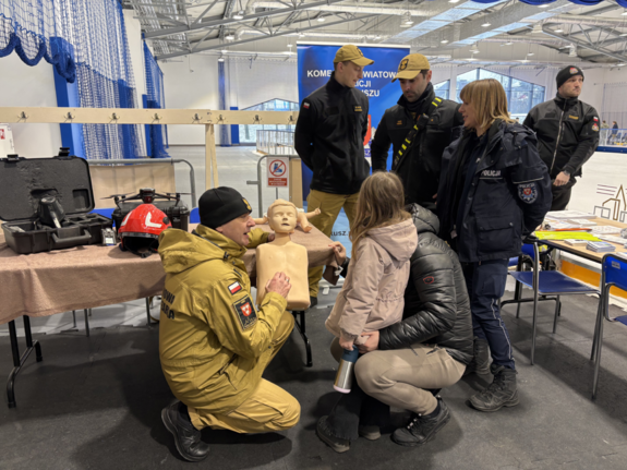 Funkcjonariusze przy stanowisku profilaktycznym z uczestnikami wydarzenia.