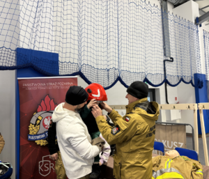 Strażak przy stanowisku profilkatycznym z uczestnikami.