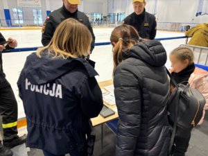 Policjantka z uczestnikami przy stanowisku profilaktycznym.