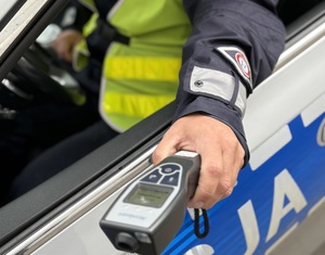 Na tle radiowozu urządzenie do pomiaru stanu trzeźwości