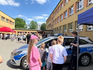 Dzieci z policjantką przy radiowozie.