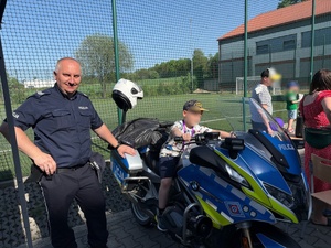 Policjant z dzieckiem na motocyklu.