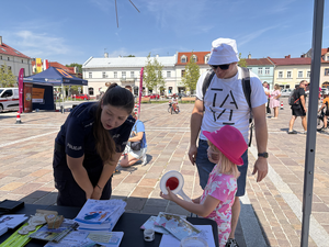 Policjantka przy stanowisku  z uczestnikami wydarzenia.