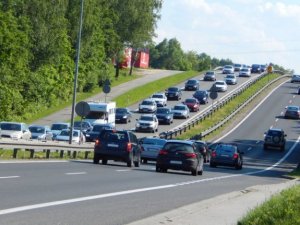 Perspektywa drogi dwujezdniowej, tzw. Zakopianki. Wzmożony ruch na jezdniach, pogoda letnia, słoneczna, widoczne bardzo dobre warunki drogowe.