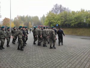 Uczniowie Zespołu Szkół w Olkuszu ZDZ przed budynkiem Miejskiego Ośrodka Sportu i Rekreacji w Olkuszu podczas paradnej musztry. Pogoda jesienna. Pochmurne niebo.