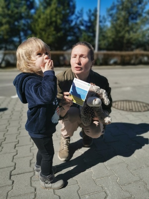Ukraiński chłopczyk przesyła rączką buziaka policjantka za otrzymanego misia