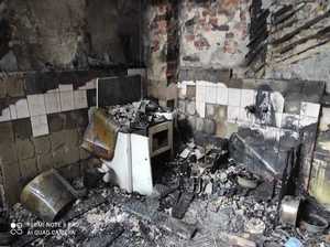 Pomieszczenie mieszkalne po pożarze pogorzelisko). Spalony sprzęt kuchenny, osmolone ściany.