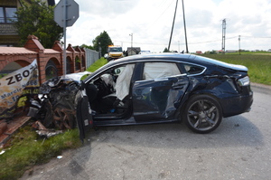 Audi po wypadku. Samochód wjechał w ogrodzenie przy [posesji. Uszkodzony przód pojazdu. na drodze i poboczu rozrzucone elementy karoserii.