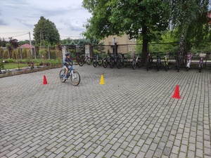 Chłopiec na rowerze w kasku ochronnym przejeżdża między pachołkami.