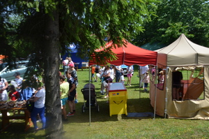 Piknik w Małobądzu. Kolorowe namioty, przy których zbierają się ludzie. Pogoda letnia, słoneczna.