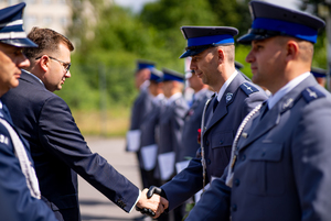 Wojewoda Małopolski podaje rękę policjantowi i gratuluje awansu.