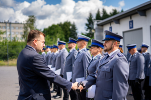 Wojewoda Małopolski gratuluje awansu policjantowi i podaje mu rękę. Policjanci stoją w równym szyku.