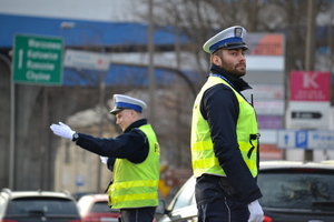 Dwaj Policjanci ruchu drogowego w odblaskowych kamizelkach. jeden z nich kieruje ręcznie ruchem