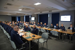 Na zdjęciu widoczni policjanci uczestniczący w odprawie  siedzący przy stołach w umundurowaniu słuzbowym