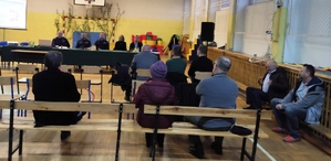 Uczestnicy debaty siedzą n wprost prelegentów.  Przy stole przedstawiciele Policji sołtys oraz dyrektor szkoły. Zdjęcie wykonane w sali gimnastycznej.