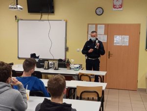 Policjant ruchu drogowego podczas spotkania z uczniami w ZS nr 1 w Olkuszu.Zdjęcie w klasie lekcyjnej, uczniowie siedzą w szkolnych ławkach.