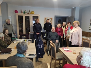 Policjantka i policjant pozują do zdjęcia z seniorami. Zdjęcie w pomieszczeniu Środowiskowego Domu Pomocy Społecznej.